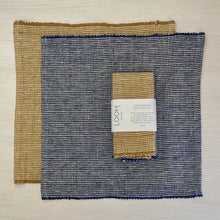 Load image into Gallery viewer, Two woven placemats with a label on a light wooden surface