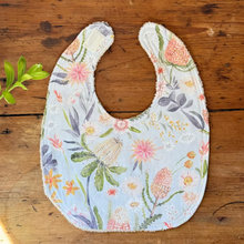 Load image into Gallery viewer, Floral-patterned baby bib on a wooden surface