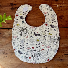Load image into Gallery viewer, Floral and bird patterned baby bib on a wooden surface