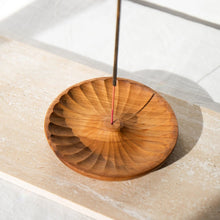 Load image into Gallery viewer, A round wooden incense holder with a scalloped edge, shown on a light stone surface with incense sticks being burned in the center.