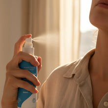 Load image into Gallery viewer, Person using a spray bottle labeled 'AMAZING' with a soft focus background
