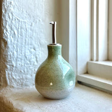 Load image into Gallery viewer, Green ceramic soap dispenser on a windowsill with a white wall background
