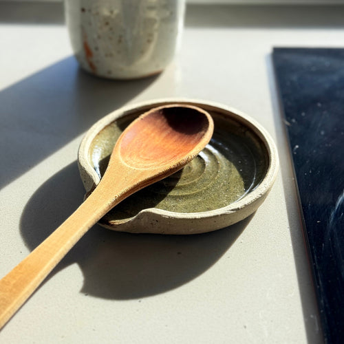 Ceramic dish with wooden spoon on a light surface, with a blurred background
