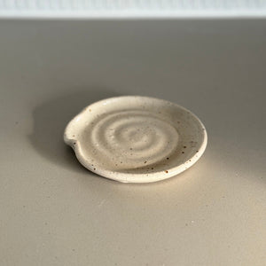 Small ceramic plate with a spiral design on a plain background