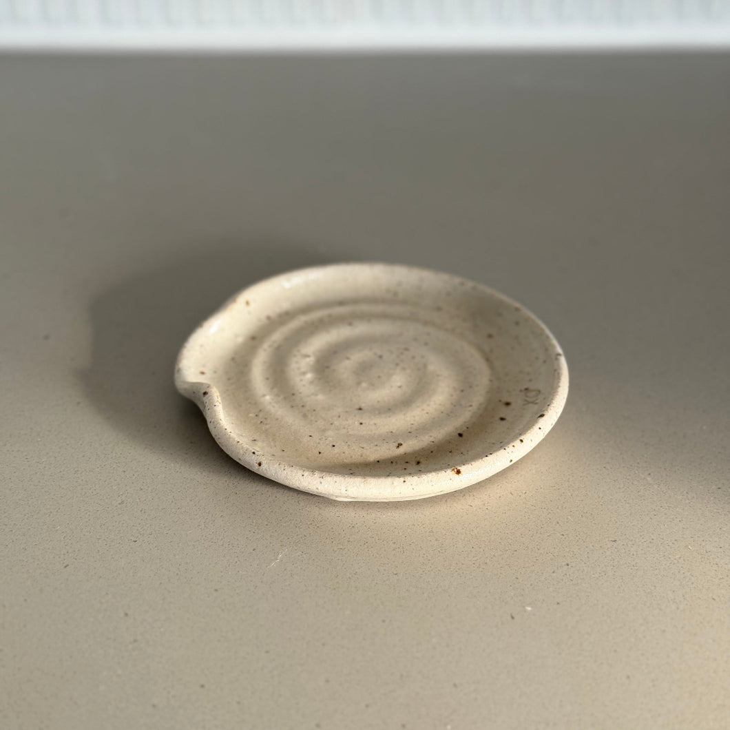 Small ceramic plate with a spiral design on a plain background