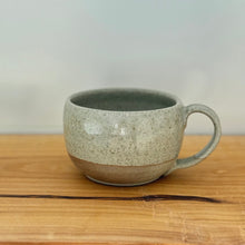 Load image into Gallery viewer, Speckled ceramic mug on a wooden surface with a plain background
