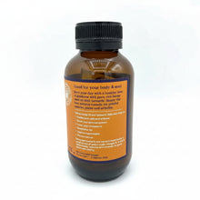 Load image into Gallery viewer, An amber glass bottle with a black ribbed cap, showing the back of its label with orange and dark blue text, set against a plain white background.
