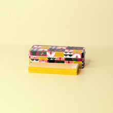 Load image into Gallery viewer, Colorful patterned box with a stack of yellow napkins on a beige background

