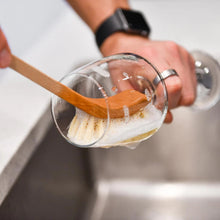Load image into Gallery viewer, Person washing a glass with a wooden spoon in a sink
