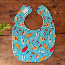 Load image into Gallery viewer, Baby bib with fish pattern on a wooden surface
