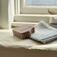 Load image into Gallery viewer, Bar of soap and a textured cloth on a windowsill
