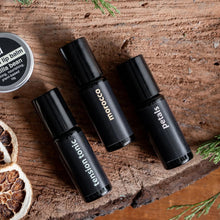 Load image into Gallery viewer, Three black rollerball bottles labeled 'Morocco', 'Tension Tonic', and 'Pecans' on a wooden surface with dried fruit and herbs.
