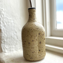 Load image into Gallery viewer, Speckled ceramic bottle on a windowsill with natural light
