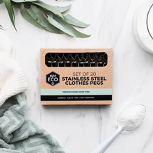 Load image into Gallery viewer, A flat-lay of a product box containing 20 stainless steel clothes pegs, styled on a white marble surface with a green towel, white towel, and a spoonful of white powder.
