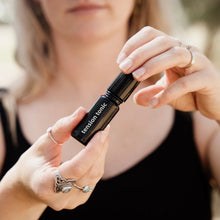 Load image into Gallery viewer, Person holding a small black container labeled 'tension tonic' with a blurred background
