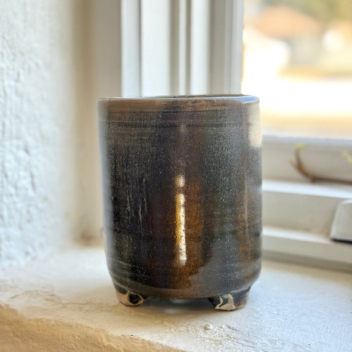 Ceramic utensil drainer with a textured surface on a windowsill